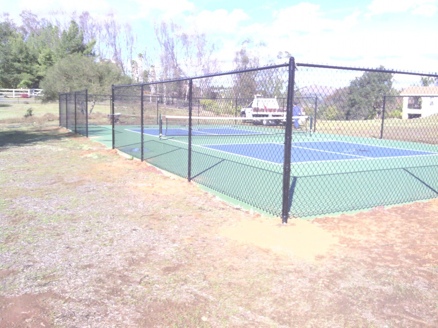 Tall chain link fencing around a tennis court