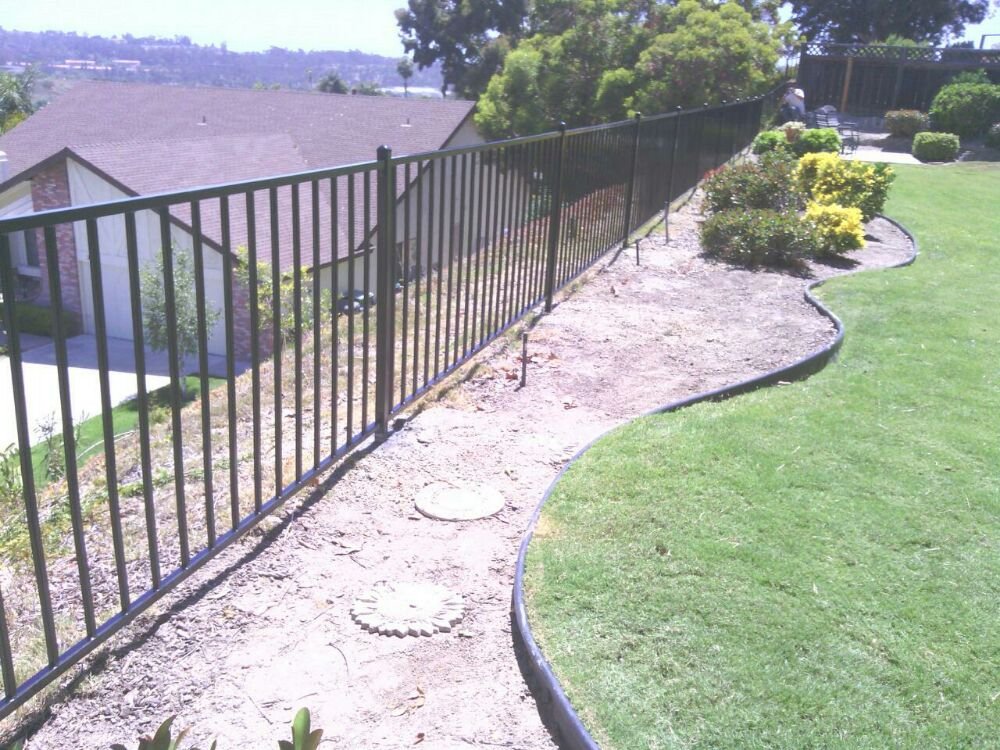 Black ornamental iron fence following a grade