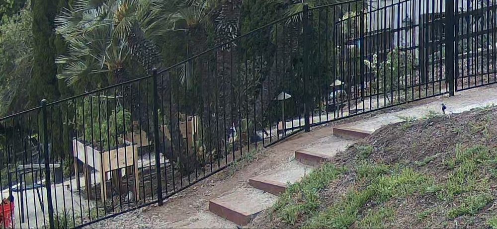 Ornamental iron fence set above a low wall beside a patio