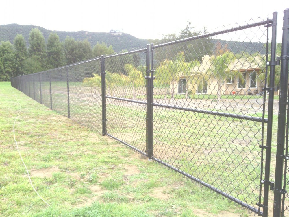 Galvanized chain link fence with a drive gate on a rural property