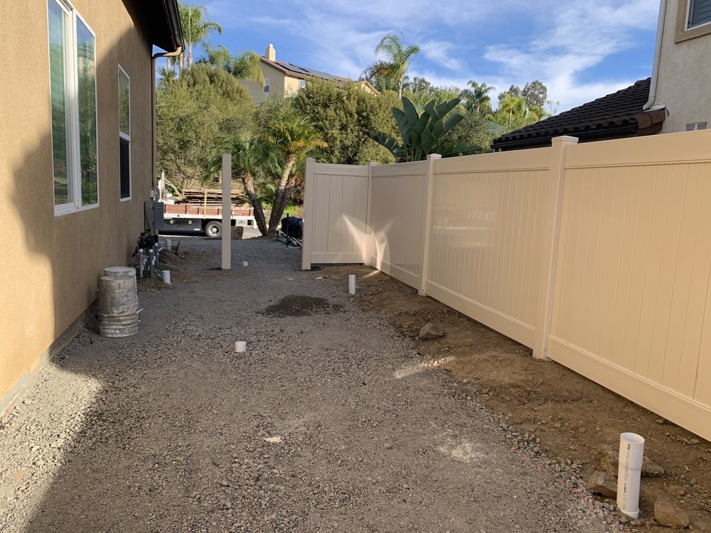 Tan vinyl privacy fence installed along a side yard